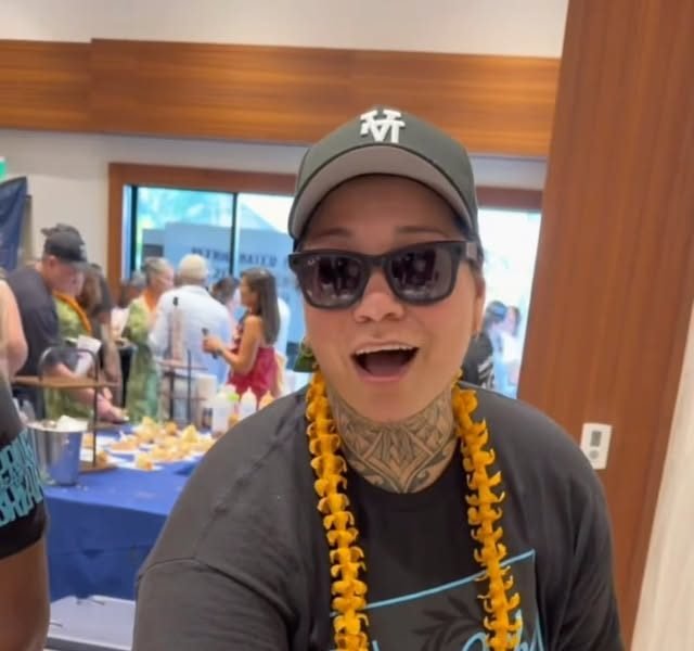 Chef Chantelle Berengue smiling in a cap and lei while catering an event