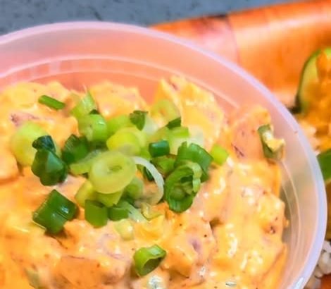 Close-up of a creamy spicy ahi poke bowl with green onions